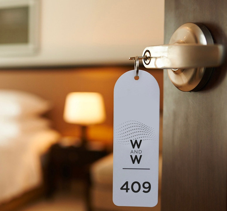 Door tag with Watches and Wonders Geneva logo and room number 409 in a hotel room. 